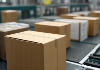 Cosmetic products being placed into boxes on a conveyor belt